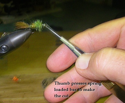Thumb presses spring loaded bar to make the cut